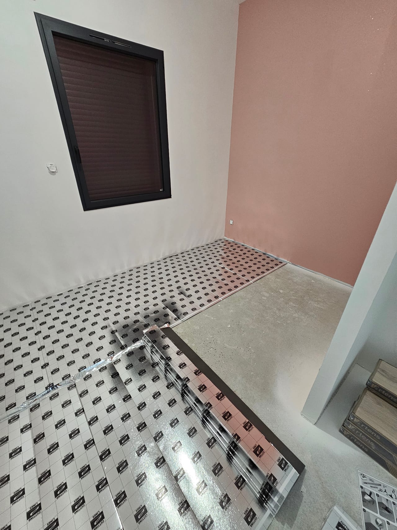 Ancien carrelage à motifs et préparation du support près d’une cloison rose