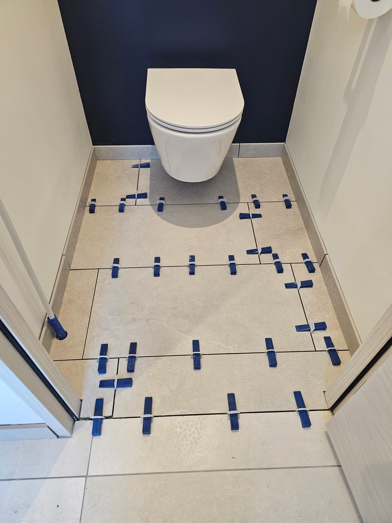 WC suspendu blanc et carrelage clair avec cales de pose
